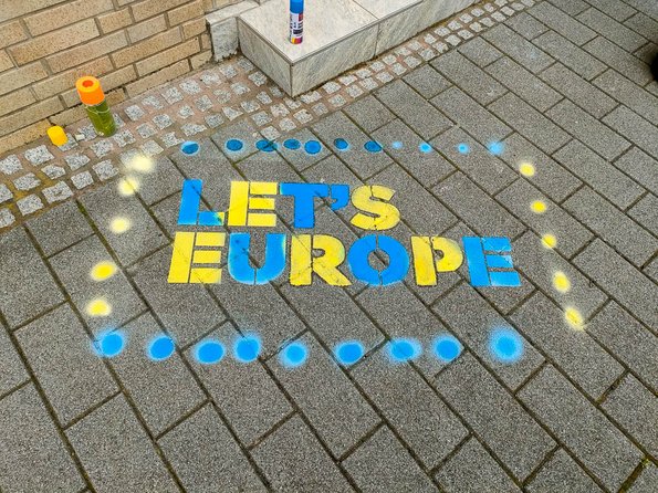 Schablone auf dem Bürgersteig mit dem Text. "Let's Europe"